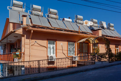 A lot of solar water heating systems on roof of house. a lot water tanks and solar panels on roof.