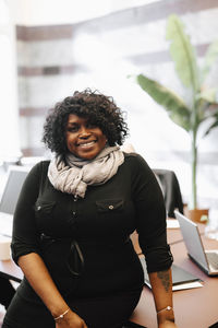 Portrait of smiling businesswoman leaning on desk at law office