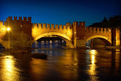 Arch bridge over river at night