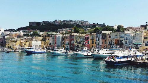 Sailboats moored on sea against buildings in city