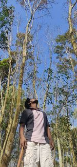Rear view of man standing by tree against sky