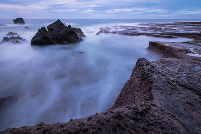 Rock formations on shore against sky