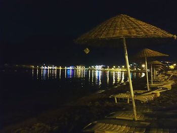 Illuminated built structure by sea against sky at night