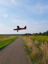 Airplane flying over field against sky