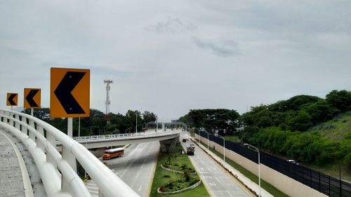 Road sign by highway against sky