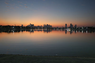 Scenic view of river by buildings against sky during sunset