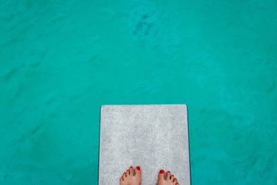 Low section of woman divingboard against swimming pool