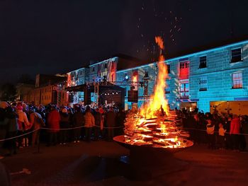 People against illuminated fire at night - bonfire