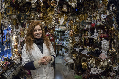 Woman smiling while standing amidst masks in store