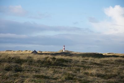 Lighthouse on field against sky