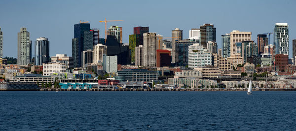 Sea by buildings against clear sky in city