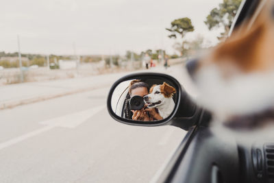 Woman photographing reflecting on side-view mirror