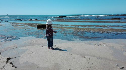 Rear view of boy on beach against sky