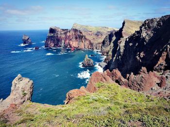 Scenic view of sea by cliff against sky