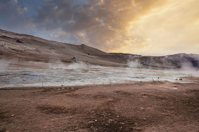 View of steam emitting from crater in geothermal area of hverir during sunset