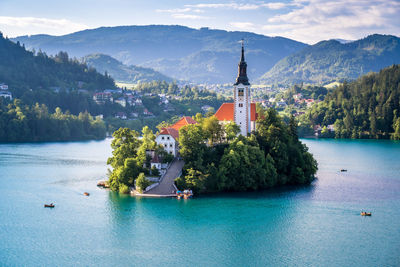 Scenic view of building in lake by mountain against sky