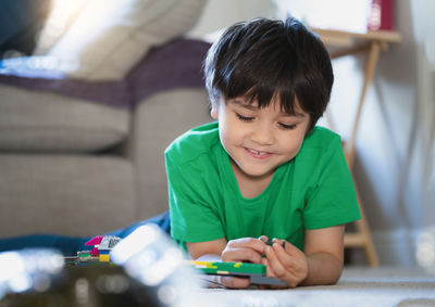 Boy holding toy while sitting at home