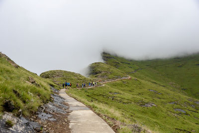 Hikers walking on mountain during foggy weather