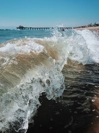 Waves splashing on shore against sky