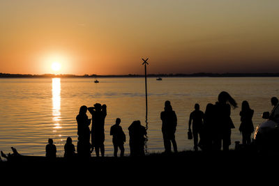 Silhouette people on beach against sky during sunset