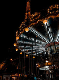 Low angle view of illuminated ferris wheel against buildings at night