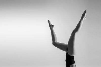 Low section of woman with arms raised against clear sky