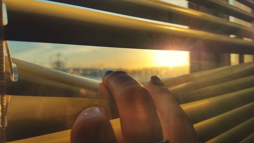 Close-up of hand on bus against sky