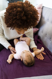 Woman looking at baby lying on sofa in living room