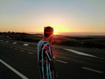 Man standing on road while looking at sunset
