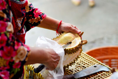 Close-up of woman cutting durian at shop