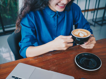 Midsection of woman holding coffee cup