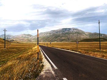 Road leading towards mountains against sky