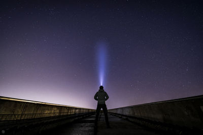 Low angle view of man standing on field against sky at night