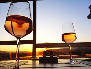 Close-up of wineglass on table against sky during sunset