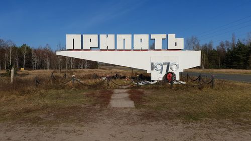 Prypiat 3d city name 1970. brown dry grass patch and blue sky. some trees in the background