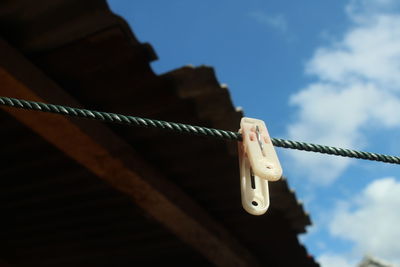 Low angle view of clothespins on rope against sky