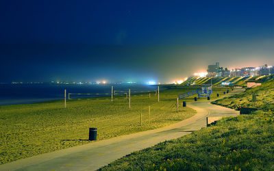 Footpath by sea against sky at night