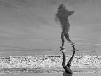 Woman standing at beach against sky