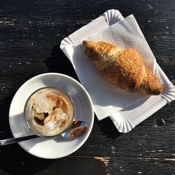 Directly above shot of iced coffee by croissant on table