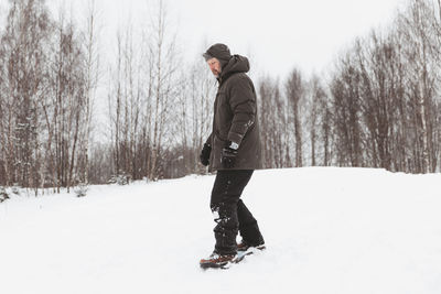 A man rides a snowskate in a winter park, healthy sporty lifestyle, rest and walk in nature