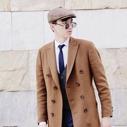 Portrait of man wearing hat standing against wall