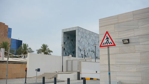Road sign by building against sky in city
