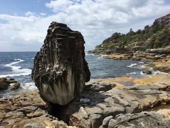 Rock formation on sea shore against sky