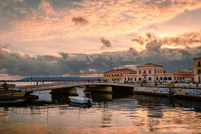 Pier over river against sky during sunset