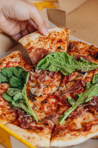 Close-up of hand holding pizza
