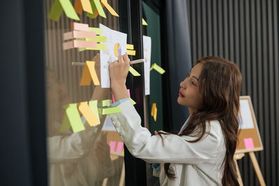 Side view of young woman using mobile phone