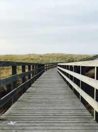 Footbridge on boardwalk against sky