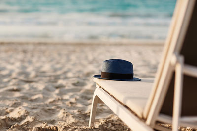 Blue hat is lying on a chaise longue on a beautiful sandy beach by the sea. space for text