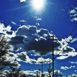 Low angle view of electricity pylon against cloudy sky