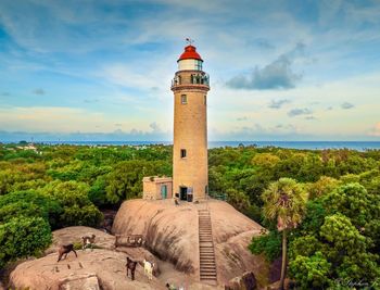 Lighthouse amidst trees against sky